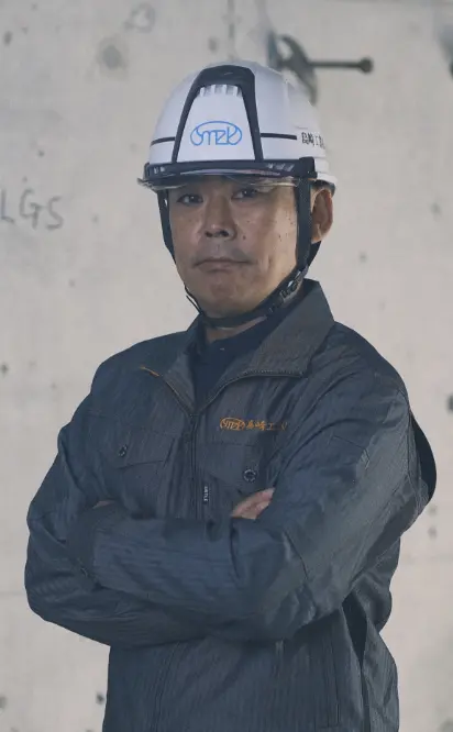  壁の前に立つヘルメットをかぶった男性の姿