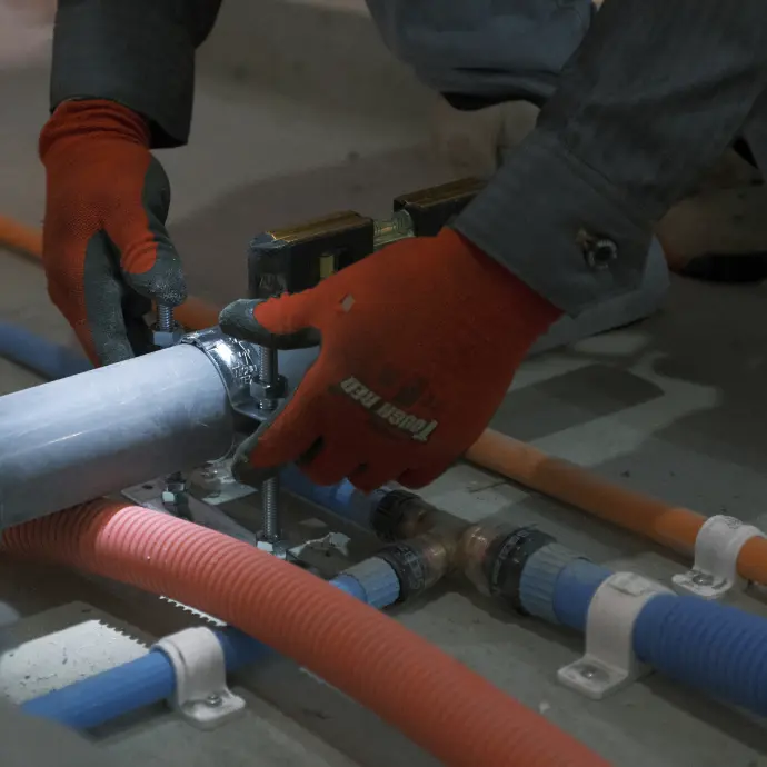 赤い手袋をはめた男性が配管を修理している様子