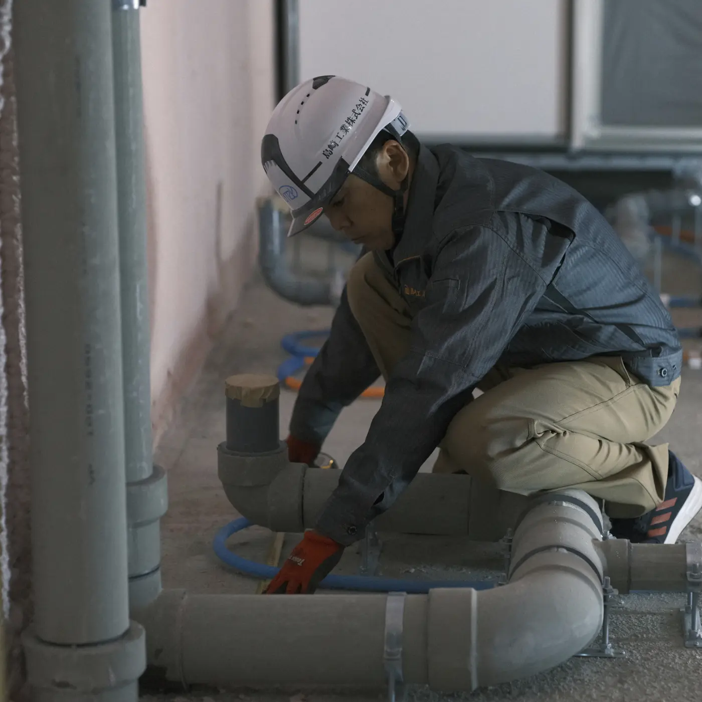 男性がヘルメットとジャケットを着て、床にひざまずいている姿