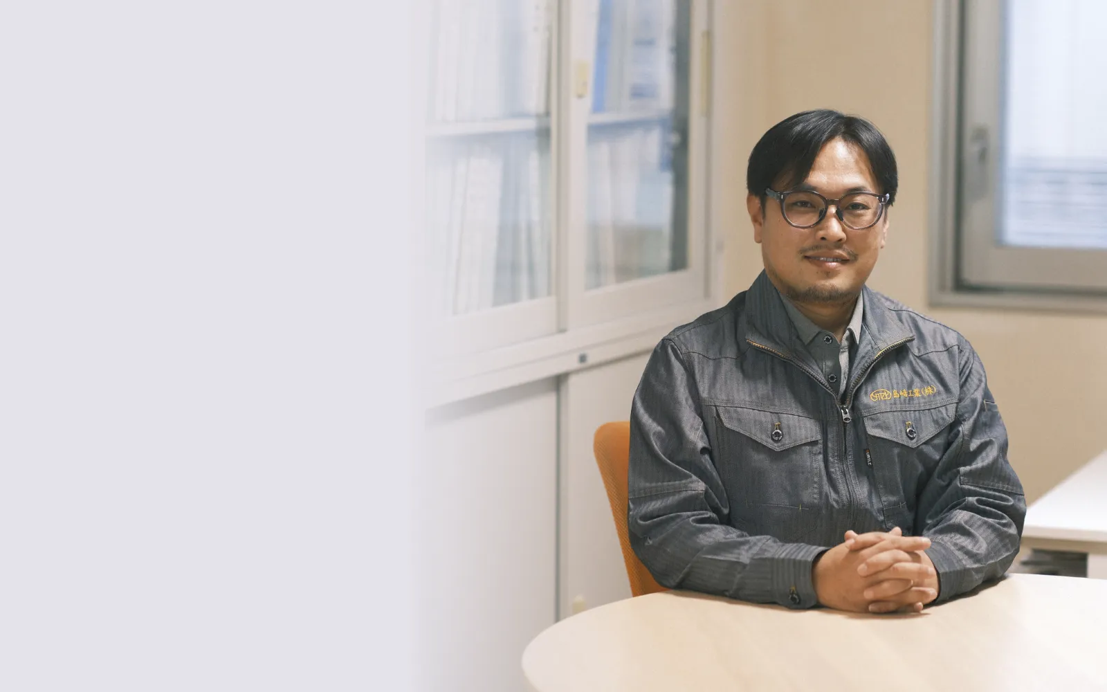  メガネをかけた男性がデニムジャケットを着用している様子