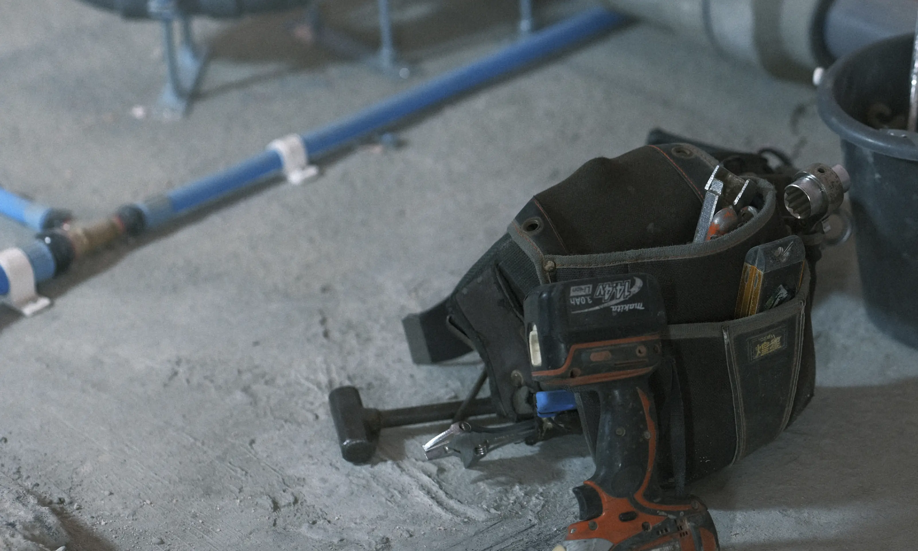 床にある工具バッグとその隣にあるパイプの様子