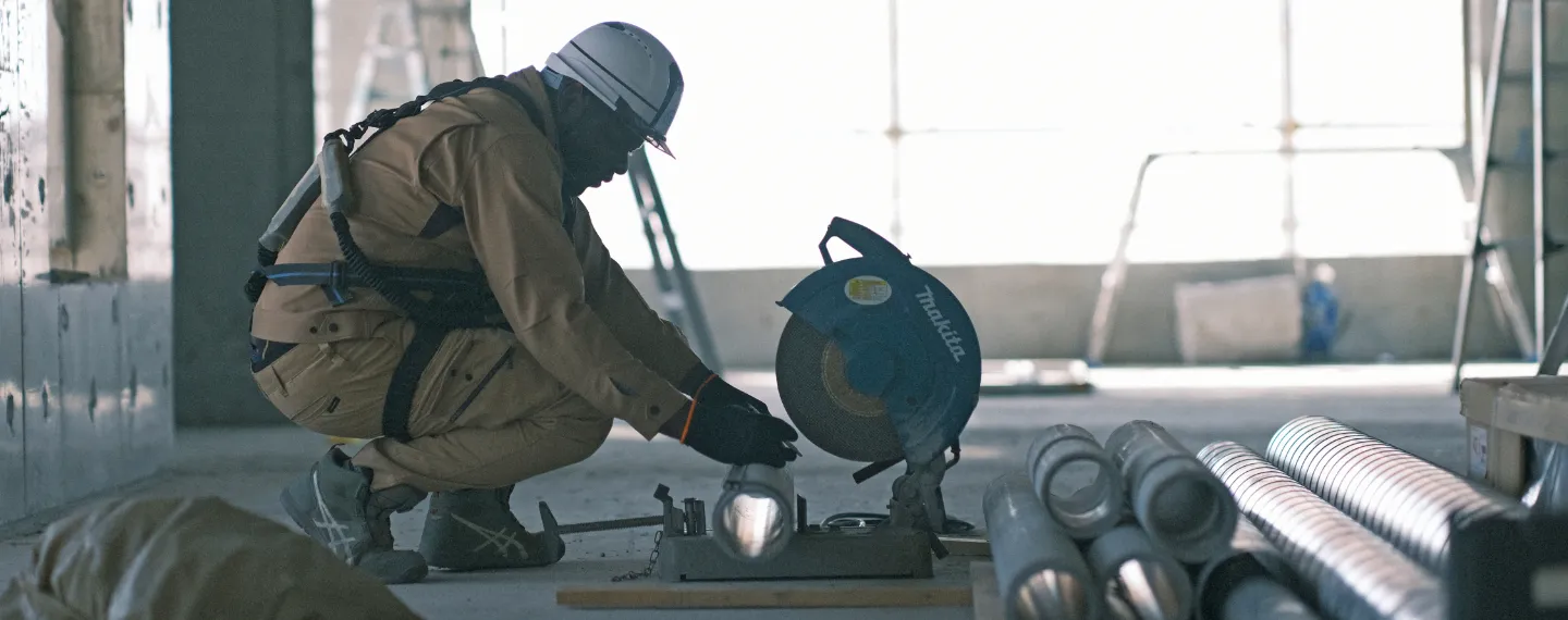 腰道具を装着した作業服姿の背中から伝わる、プロフェッショナルな職人の雰囲気と現場の臨場感