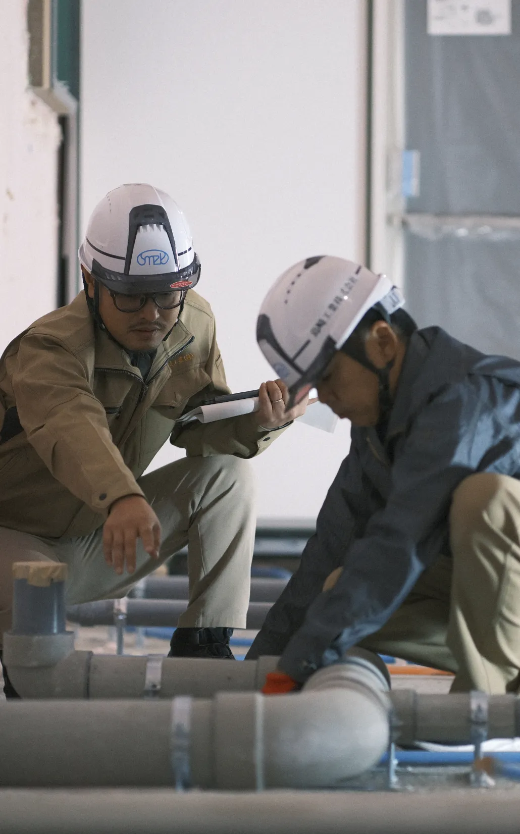 建設現場でタブレットを手に笑顔で打ち合わせをする作業員たち