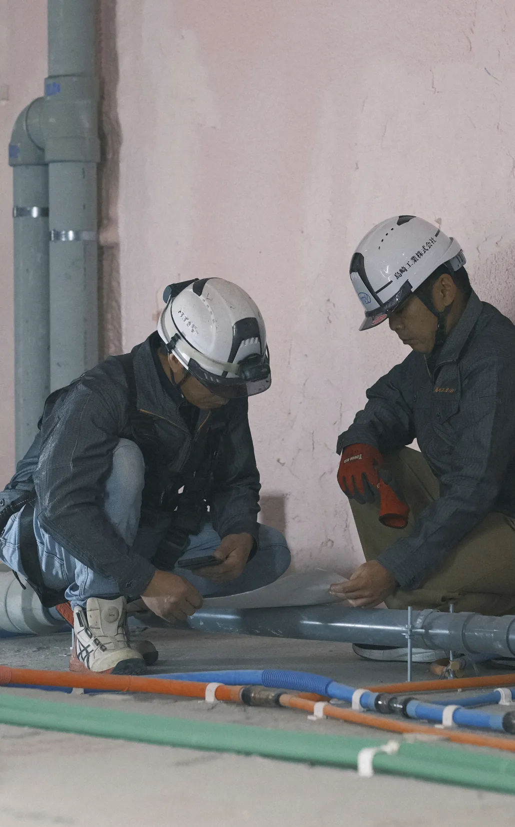 現場で配管の状態を指差し確認しながら指示を出すスタッフ