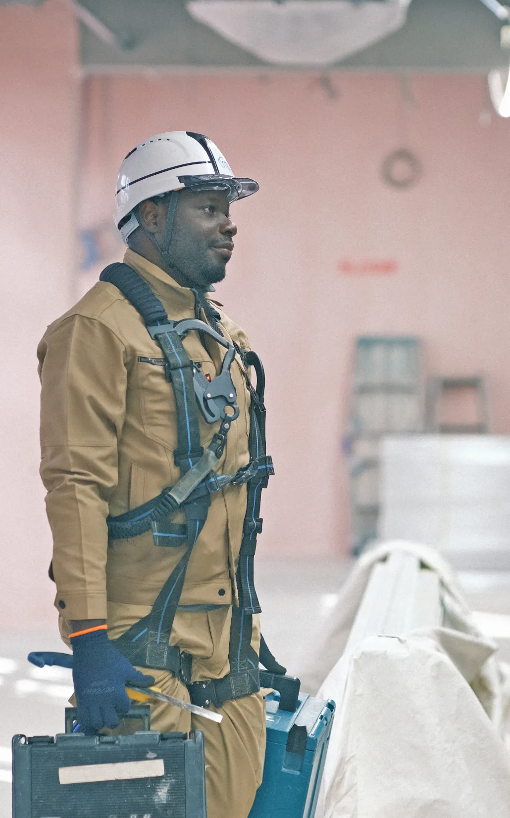 建設現場でインパクトドライバーを使い、天井の配管を固定する作業員