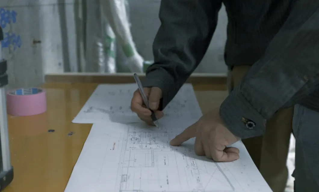 図面を広げ、ペンで書き込みをしながら確認作業を行う手元のアップ